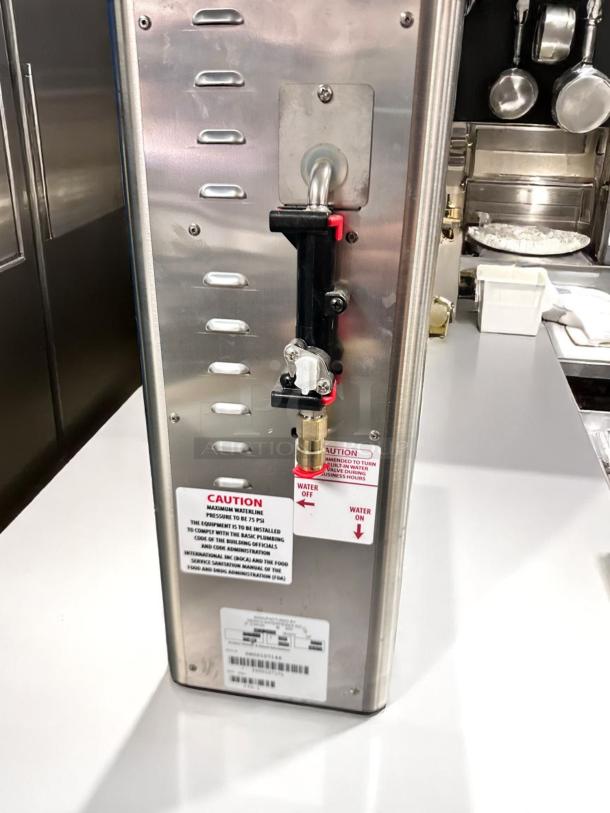 Newco FPM-1 stainless steel cold beverage dispenser, manual pour, excellent condition, fully tested, caution label visible.