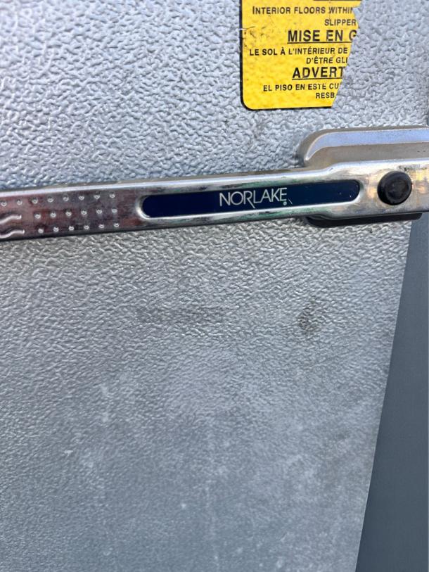 Norlake walk-in cooler with double doors. Features heavy-duty insulated panels. Yellow safety label visible.