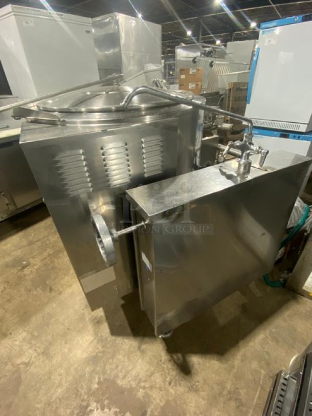 Commercial stainless steel natural gas tilting steam kettle with swing spout faucet, mounted on legs, in good condition.