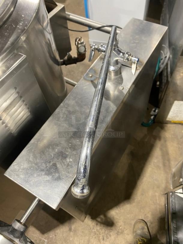 Commercial stainless steel tilting steam kettle on legs, with natural gas power and swing spout faucet, in used condition.