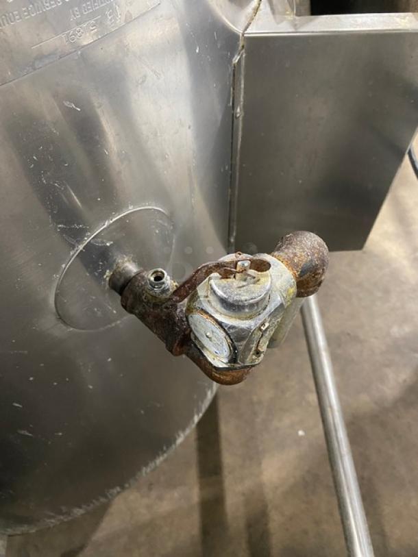 Commercial stainless steel tilting steam kettle with swing spout faucet, on legs. Natural gas powered. Some visible wear.