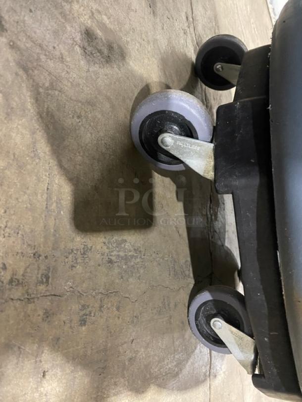 Rubbermaid BRUTE Series gray 44-gallon commercial trash container with dolly, sturdy wheels visible, excellent condition.