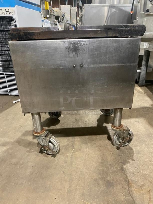 Commercial stainless steel single burner stock pot range, natural gas powered, mounted on casters, showing wear.