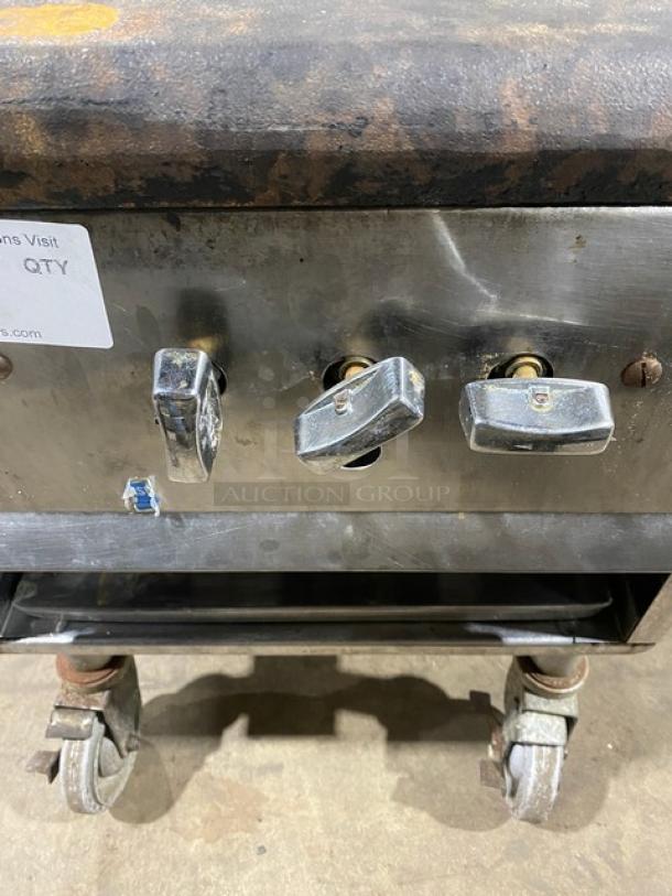 Commercial stainless steel single burner stock pot range on casters, natural gas powered, showing control knobs and wheels.