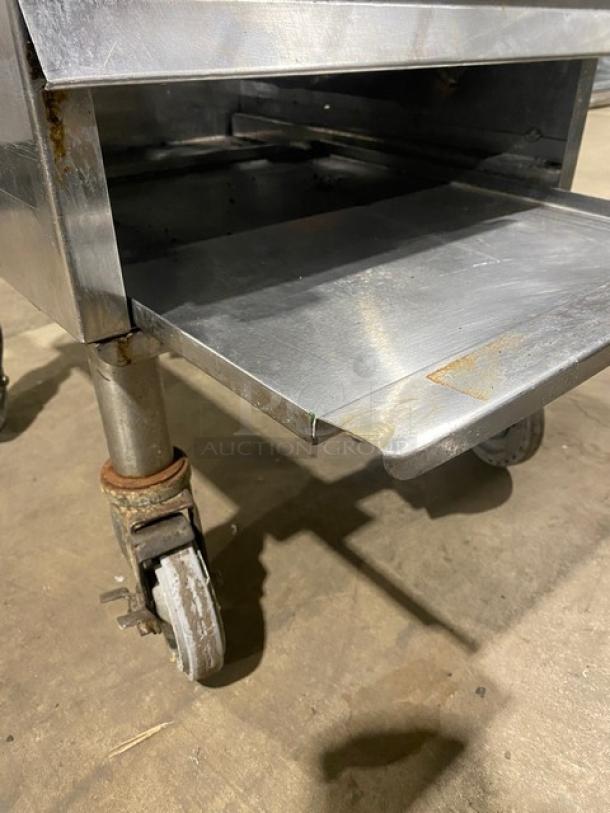 Commercial stainless steel natural gas-powered stock pot range, single burner, on casters. Rust visible, used condition.