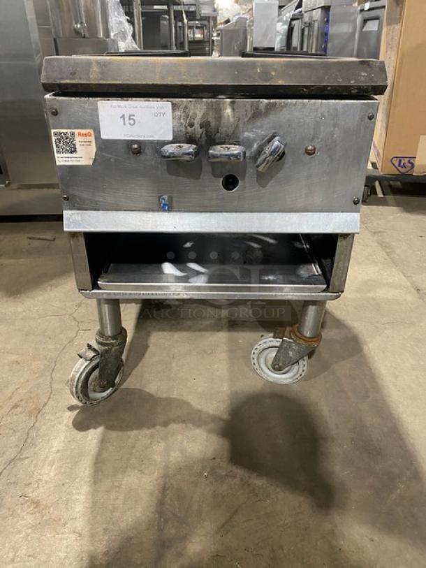 Commercial stainless steel natural gas single burner stock pot range on casters, used condition, three control knobs visible.
