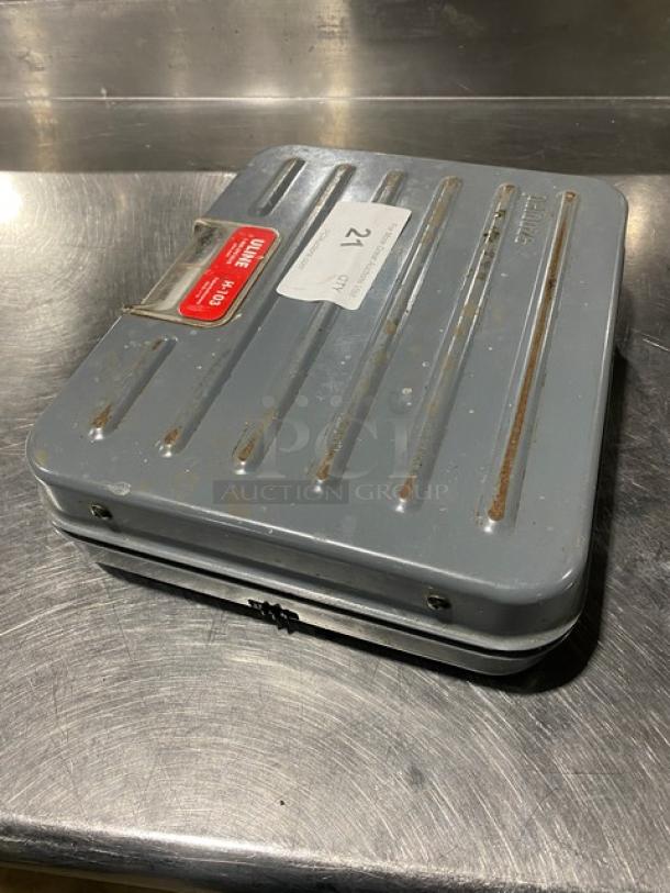 Rubbermaid FG4100UD 100 lb. analog shipping scale, briefcase-style. Minor wear visible, metallic case, model label on top.