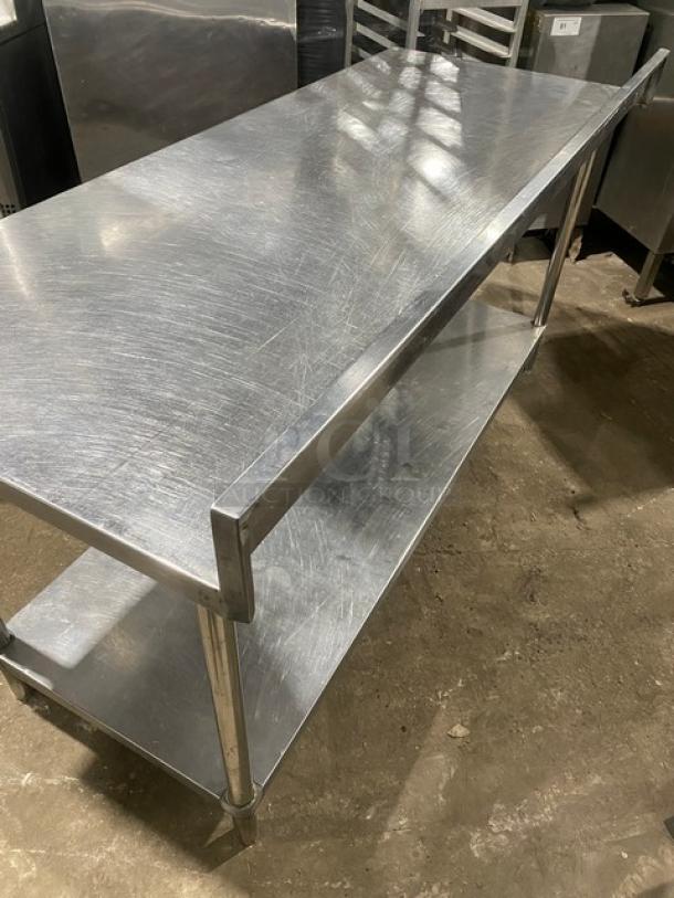 KCS stainless steel worktop table with undershelf and upturned backsplash, on legs. Slight wear visible.