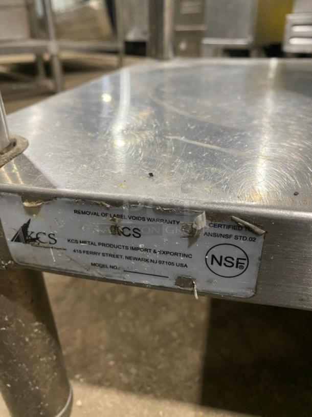 KCS commercial stainless steel worktop table with undershelf and up-turned backsplash. Features label with certification and maker's address.