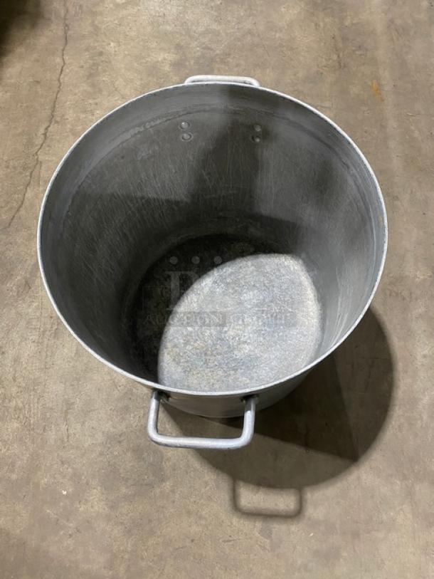 Commercial heavy-duty round stock pot with handles. Made of metal, shows signs of use, suitable for large volume cooking.