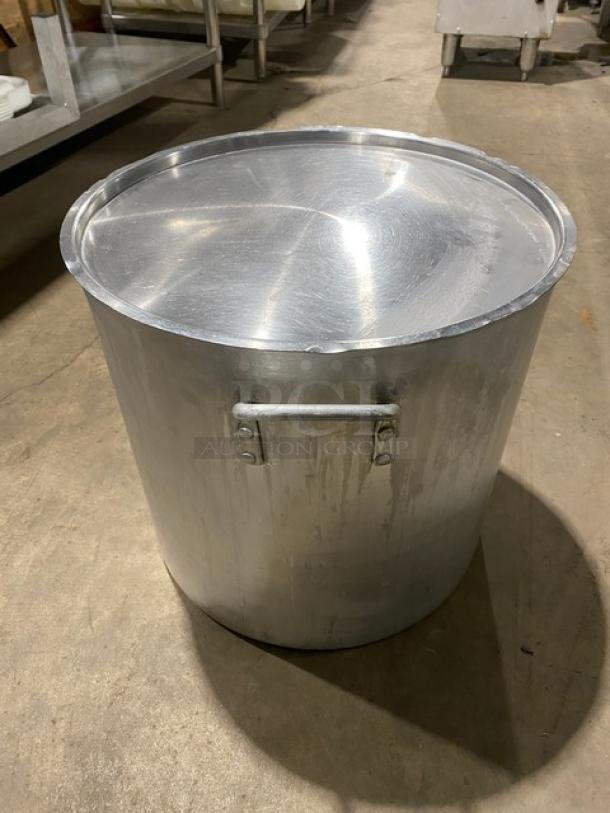 Commercial heavy-duty round stock pot with handles and lid. Visible wear indicating prior use. Ideal for large-scale cooking.