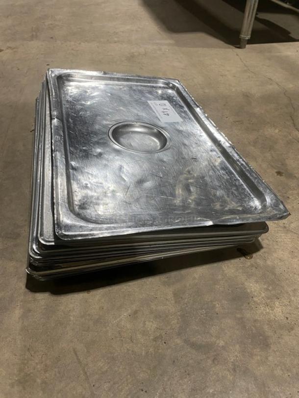 Commercial stainless steel steamtable pan lids, stack of several, used condition, some surface scratches, rectangular with center handle indentation.
