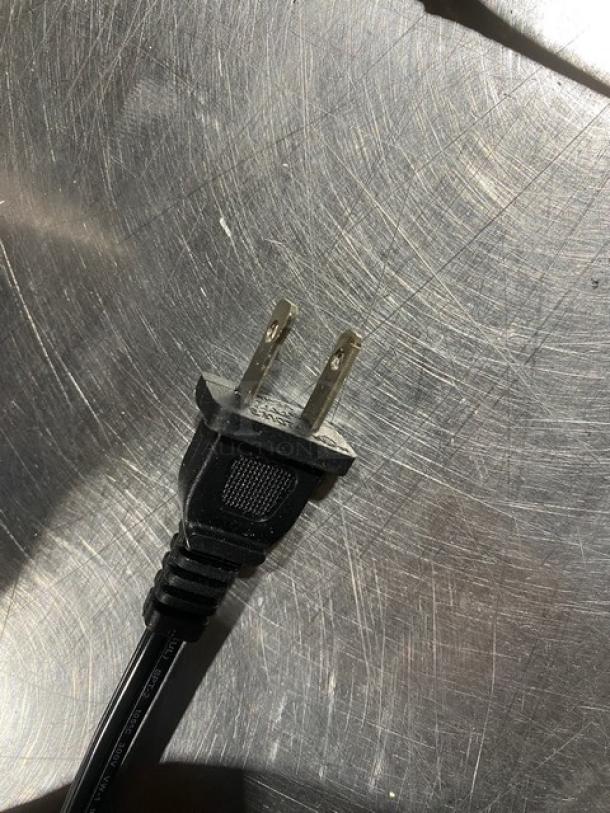 Two-prong power cord for Brentwood TS-1001 knife sharpener on a metallic surface.