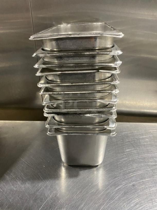 Stack of 11 commercial stainless steel hotel pans on metal surface, used condition. Ideal for catering or restaurant use.