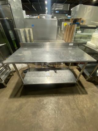 Commercial stainless steel worktop table with undershelf and up-turned backsplash, on legs, in good condition.