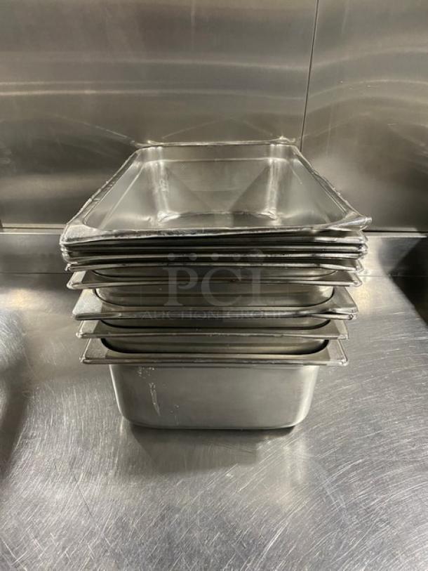 Stack of commercial stainless steel hotel steamtable pans in good condition, showing smooth surfaces and slight wear.