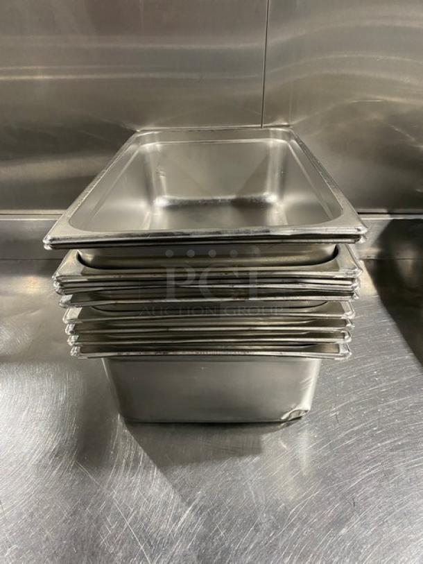 Stack of stainless steel hotel steamtable pans, commercial grade, polished finish, slight wear, suitable for food service.