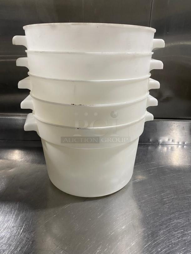 Stack of five commercial white round food storage containers with handles on a metal surface. Good condition.