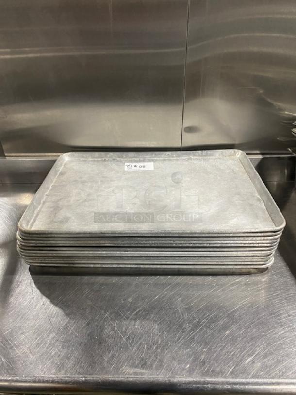 Stack of commercial baking sheet pans, metal construction, used condition, lot of 12, suitable for high-volume baking.