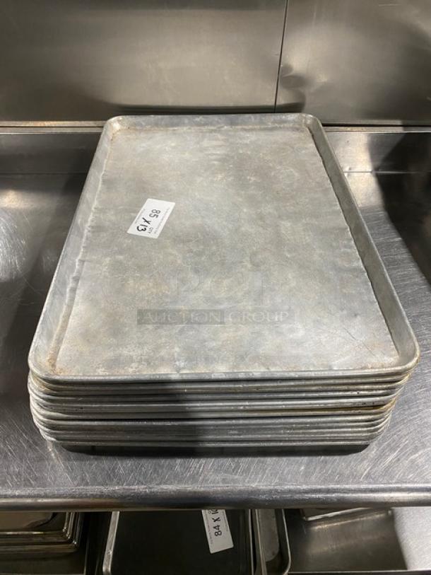 Commercial baking sheet pan stack, used condition. Includes 13 pans. Silver metal, industrial size. Tag reads "86.7 13".