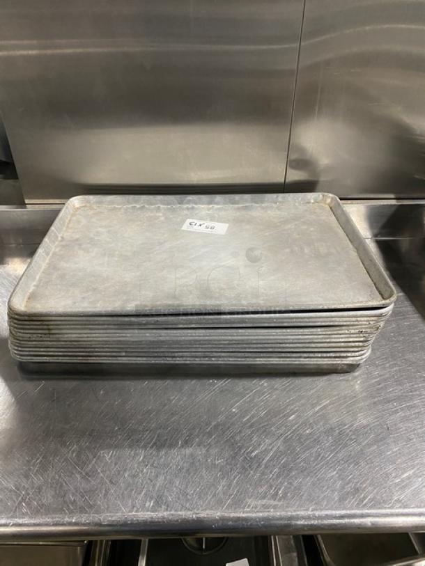 Stack of commercial baking sheet pans, used condition, dimensions 13x, visible label indicating price.