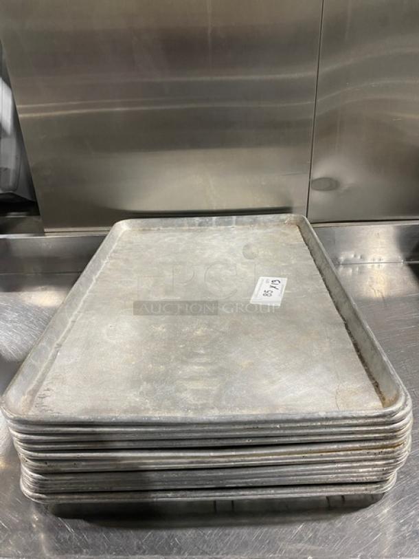 Stack of commercial baking sheet pans in used condition, with a tag indicating "85-25". Ideal for bulk baking needs.
