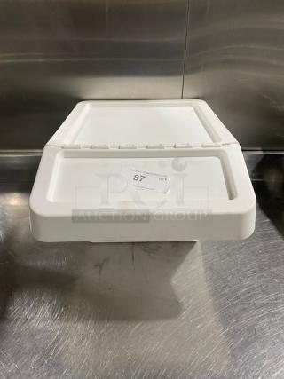 Commercial white stackable countertop food ingredient bin with hinged lid, sticker labeled "87 OTY," on stainless steel surface.