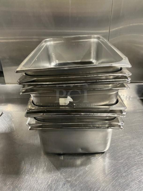 Stack of commercial stainless steel hotel steamtable pans, shown in a kitchen setting. Visible label shows condition as new.