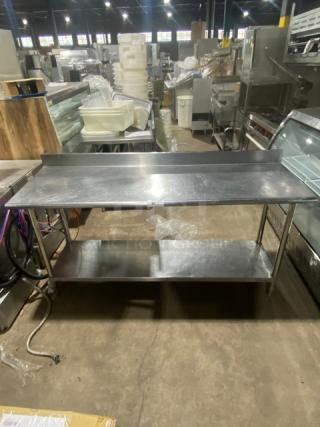 Commercial stainless steel worktop table with undershelf, up-turned back splash, and sturdy legs; in used condition.