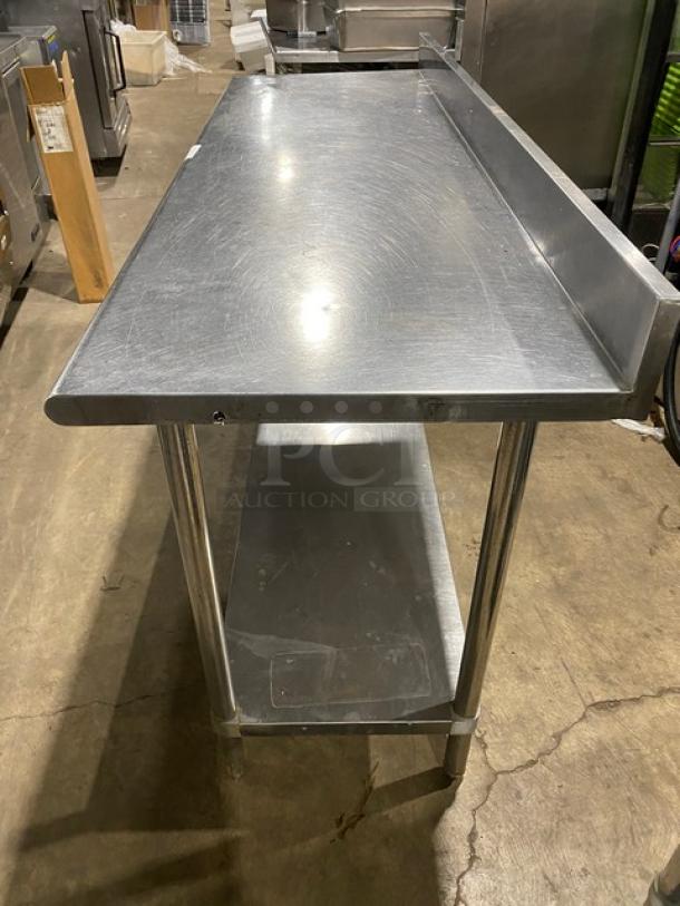 Commercial stainless steel worktop table with undershelf and up-turned backsplash. Features sturdy legs, good condition.