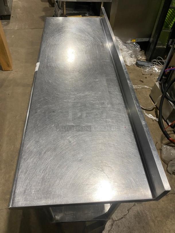 Commercial stainless steel worktop table with single undershelf and upturned back splash. Mounted on sturdy legs.