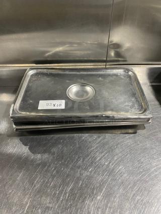 Stainless steel steamtable pan lid stack with central handle, labeled "93 X 10" indicating quantity. Used condition.