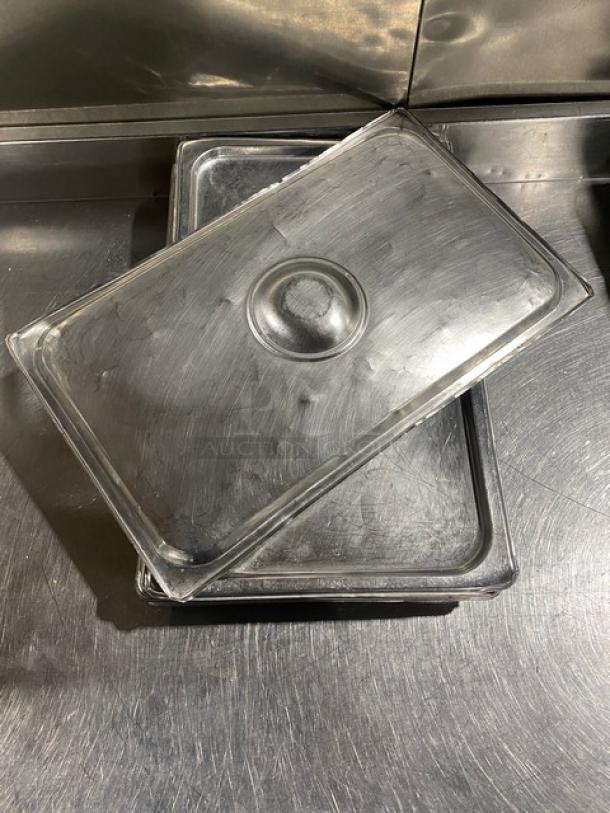 Commercial stainless steel steamtable pan lid, rectangular with central handle. Visible wear; durable kitchen essential.