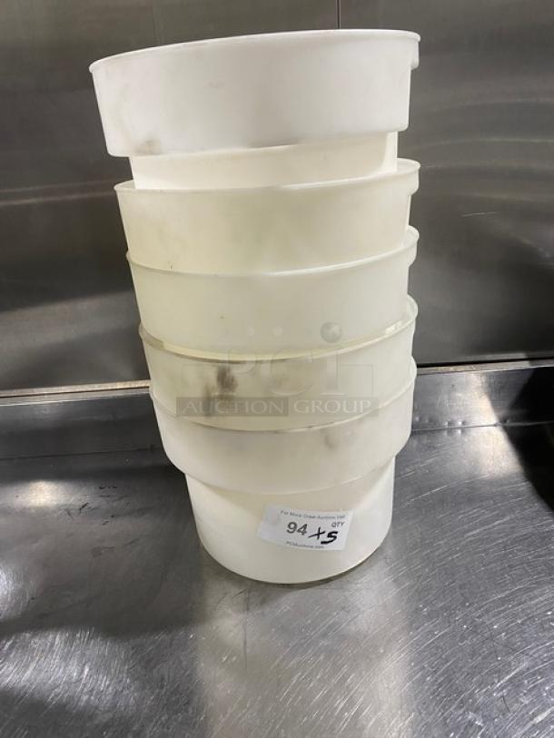 Stack of commercial white round food storage containers with handles, slightly worn, on a metal surface. Label reads "94 +5."