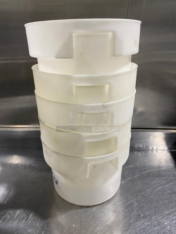 Stack of commercial white round food storage containers with handles, shown in used condition on a metal surface.