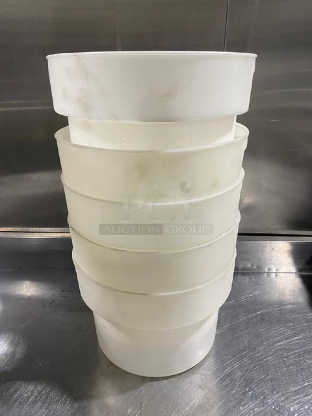 Stack of commercial white round food storage containers with handles, showing slight wear; ideal for bulk storage.