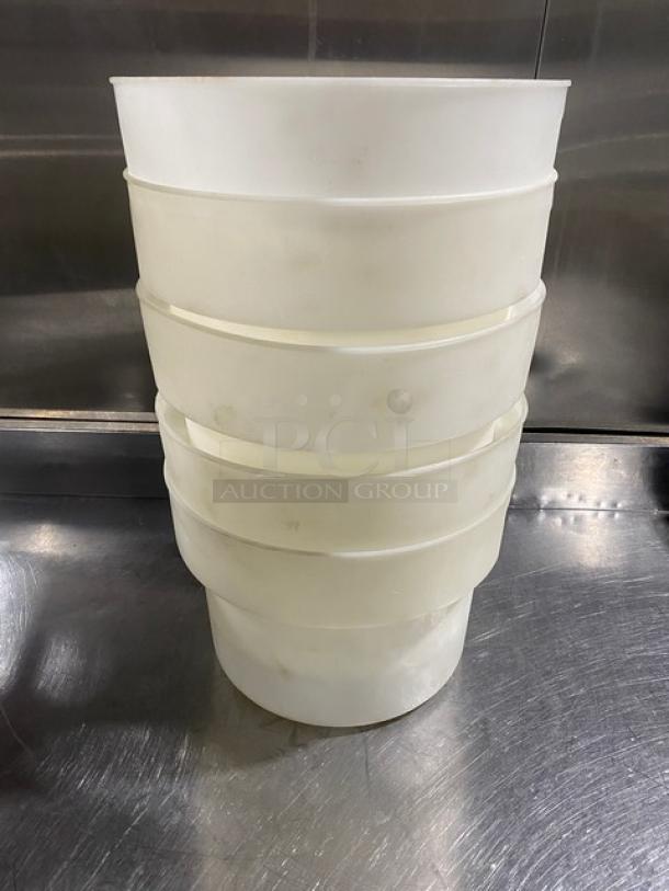 Stack of five commercial white round food storage containers with handles. Used condition, suitable for kitchen storage.