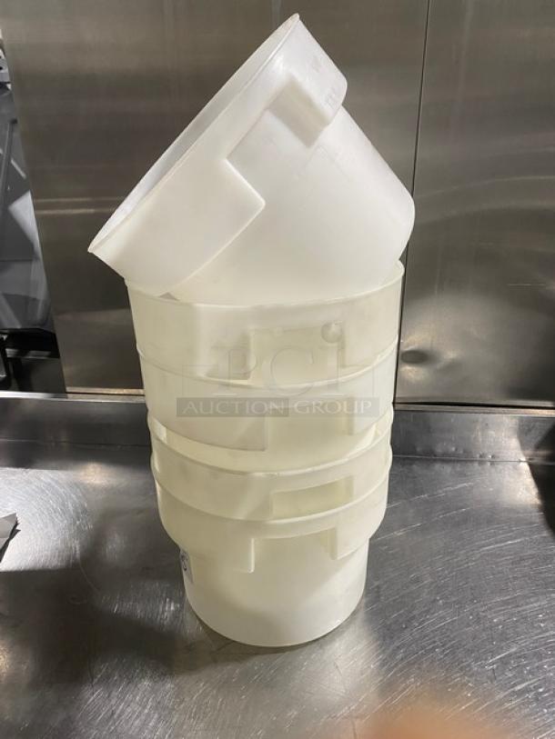 Stack of white round commercial food storage containers with handles, in used condition. Four containers shown, suitable for bulk storage.