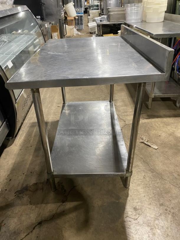 Commercial stainless steel worktop table with undershelf and up-turned back splash. Features sturdy legs, in good condition.