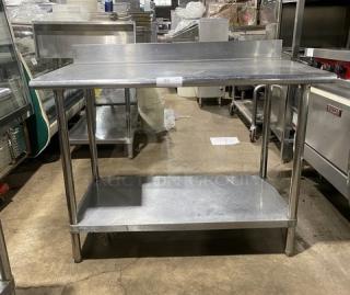 Commercial stainless steel worktop table with undershelf, up-turned backsplash, and sturdy legs. Good condition.