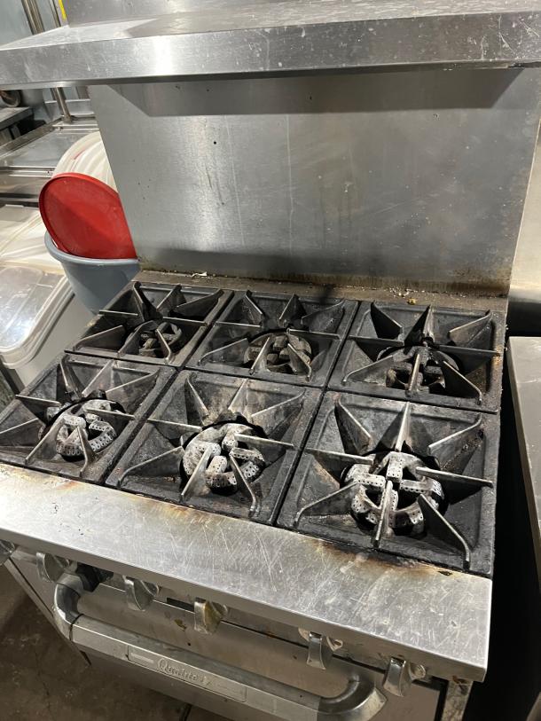 Qualite stainless steel 6-burner gas range/oven combo with backsplash, overhead salamander shelf, and wired oven rack.