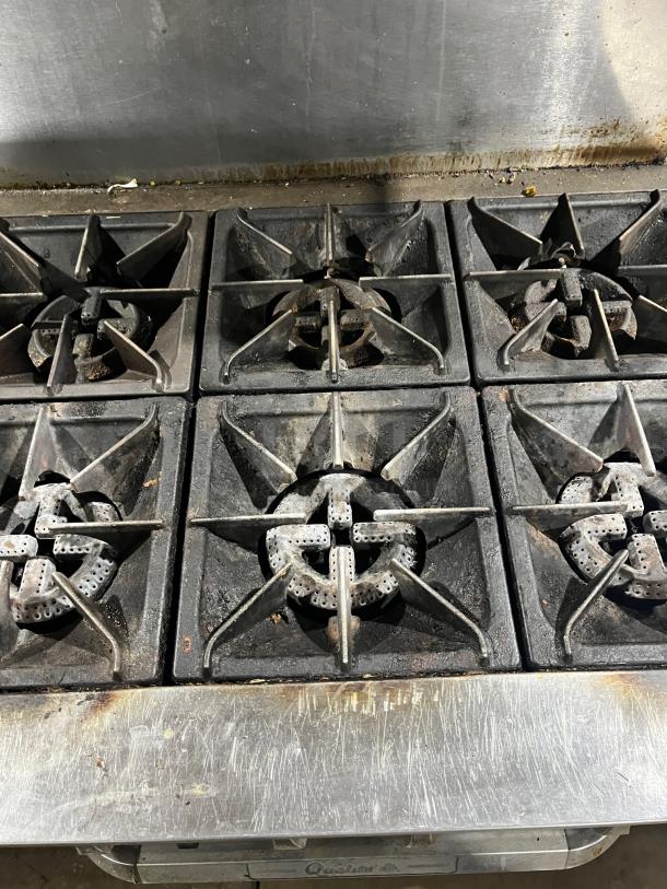 Qualite Commercial Stainless Steel 6-burner range/oven combo with backsplash, overhead salamander shelf, and wired oven rack.