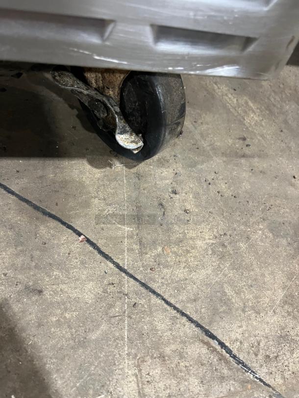 Close-up of a caster wheel on an Alto-Shaam ASC-4G convection oven, showing worn condition on a concrete floor.