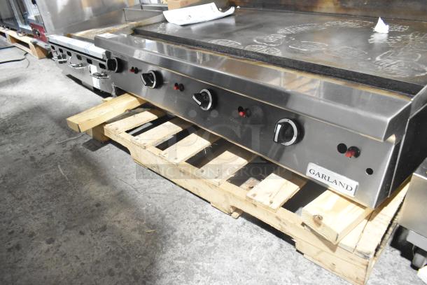 Garland Stainless Steel Commercial Griddle on wooden pallet, featuring multiple control knobs, in good condition.