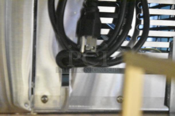 Coiled power cord near stainless steel panel of Avantco 178UBB4GHCS fridge, highlighting electrical component.