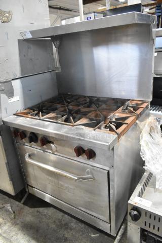 Vulcan stainless steel commercial gas range with 6 burners, oven, over shelf, and backsplash. Used, with visible signs of wear.