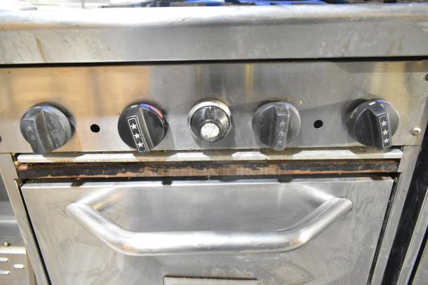 Tri-Star TSR-1 commercial range, stainless steel, with 4 burners, oven, salamander cheese melter, and backsplash. Shows wear.