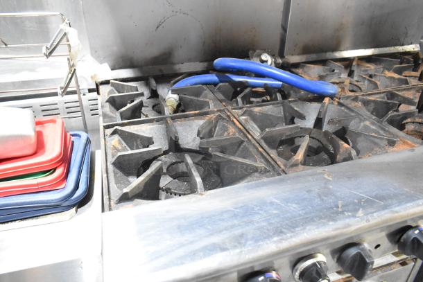 Tri-Star TSR-1 stainless steel 4-burner range with oven, salamander cheese melter, and backsplash, showing wear.