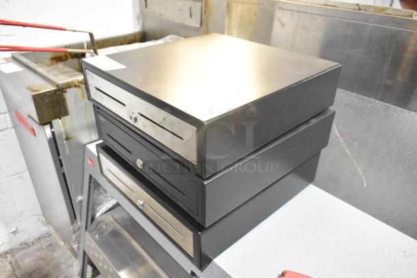 Stack of three black metal cash drawers with slotted fronts and locks, showing light wear. Auction item offers three times your bid.