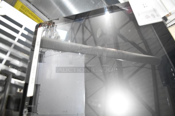 POS monitor in metallic frame, reflective screen surface, equipment visible in background. Condition appears used.